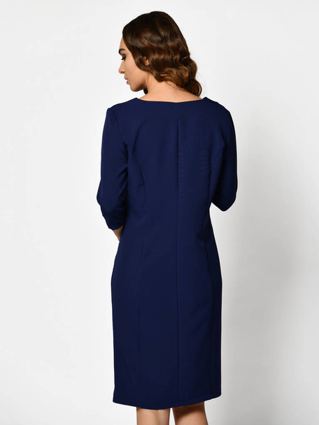 Young beautiful woman posing in new dark blue fashion winter dress backside rear view - Photo, Image