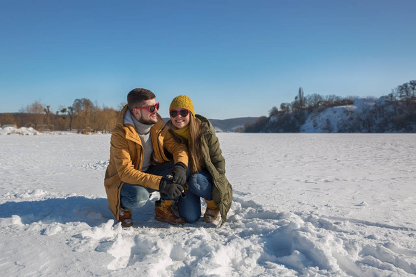 Ένα ζευγάρι ερωτευμένων νέων ανθρώπων είναι το γέλιο στη φωτογραφική μηχανή. Ηλιόλουστη μέρα του χειμώνα. - Φωτογραφία, εικόνα