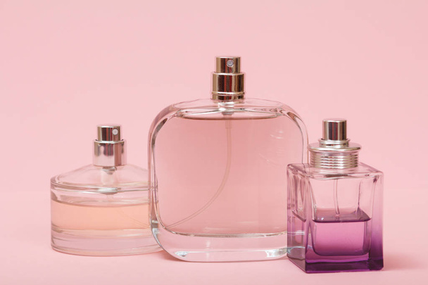 Three bottles with women perfume in a pink background. Women products. - Photo, image