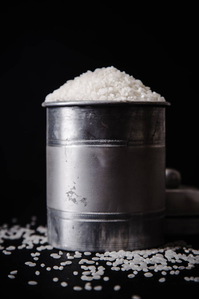 Arborio rice in metallic tin on black background - 写真・画像