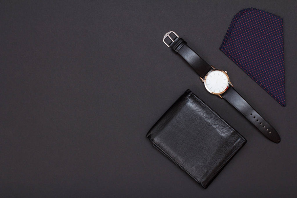 Leather purse, watch with a black leather strap and handkerchief on black background. Accessories for men. Top view with copy space. - Photo, Image