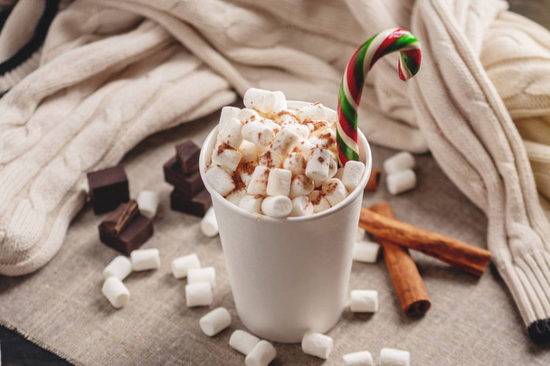 Une tasse de chocolat chaud avec guimauve sur le dessus et un bâton de sucette sur le fond de chocolat et de cannelle. Le concept d'une maison de vacances de Noël confortable
 - Photo, image
