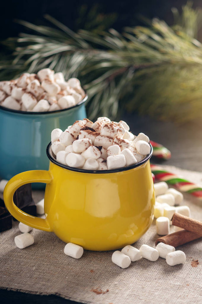 Tazze di cioccolata calda con marshmallow in cima e un bastoncino di lecca-lecca sullo sfondo di cioccolato e cannella. Il concetto di un'accogliente vacanza a casa di Natale
 - Foto, immagini