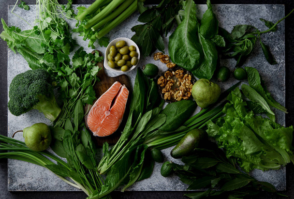 Świeże warzywa zdrowy z warzywa i owoce z orzechami włoskimi i surowego stek z łososia na szarym tle, zdrowa żywność składniki koncepcja  - Zdjęcie, obraz
