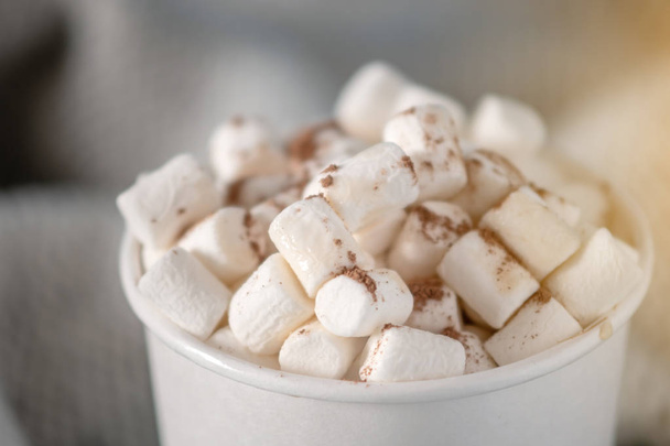 White paper Cup of hot chocolate with marshmallow on top on blue background. Cozy warm winter card - 写真・画像