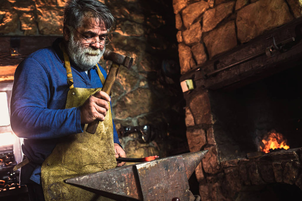 kézi kovácsolás az olvadt fém a az üllőt a kovácsműhely, a szikra tűzijáték Kovács - Fotó, kép