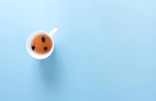 Tee aus Wildrose in weißer Tasse, auf blauem Hintergrund. - Foto, Bild