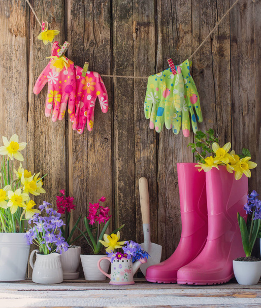 rubber boots and spring flowers on wooden background - Foto, Imagem