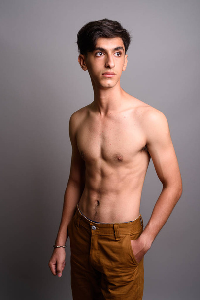 Young handsome Persian teenage boy shirtless against gray backgr - Foto, immagini