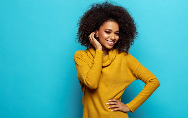 Smiling black woman with copy space wear yellow cardigan isolated on blue background - Фото, зображення