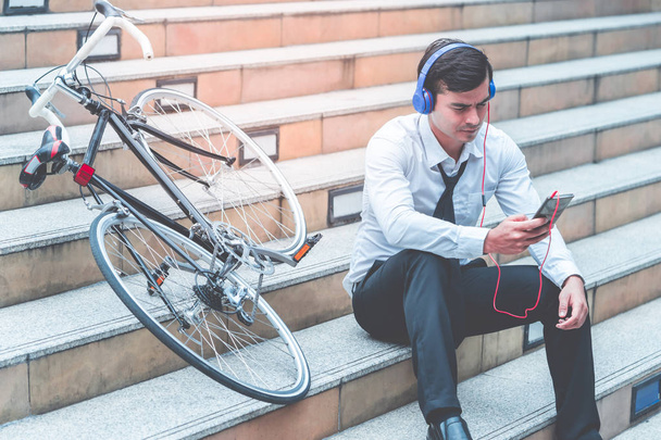 Uomo d'affari è rilassante ascoltare musica con la sua bicicletta sul lato
 - Foto, immagini