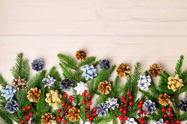 Christmas composition of fir branches decorated with bows, pine cones and red berries - Фото, изображение