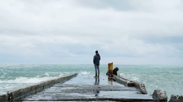 Un hombre trata de escapar de las grandes olas en el muelle, en cámara lenta
 - Metraje, vídeo
