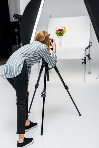 back view of young woman shooting beautiful flowers in professional photo studio - Zdjęcie, obraz