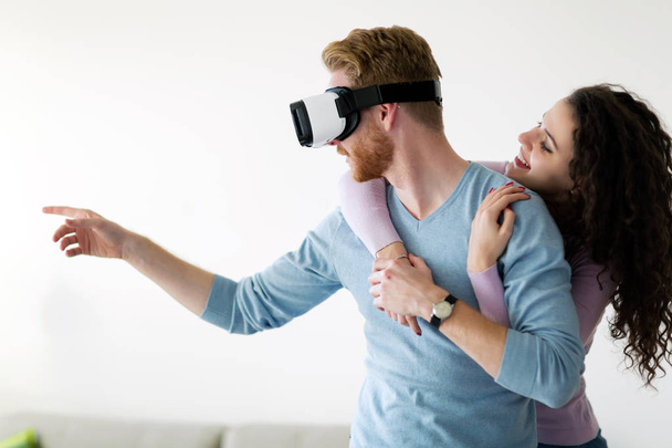 Attractive young couple trying virtual reality headset at home - Foto, afbeelding