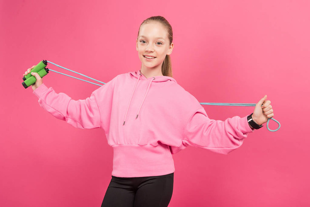 happy child in sportswear holding skipping rope, isolated on pink - Фото, зображення
