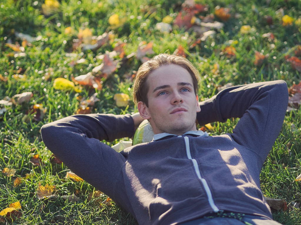 Joueur de football allongé dans l'herbe avec le football dans le parc un jour ensoleillé d'automne
 - Photo, image