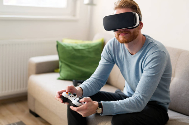 Handsome young man playing video games with virtual reality headset - Fotoğraf, Görsel