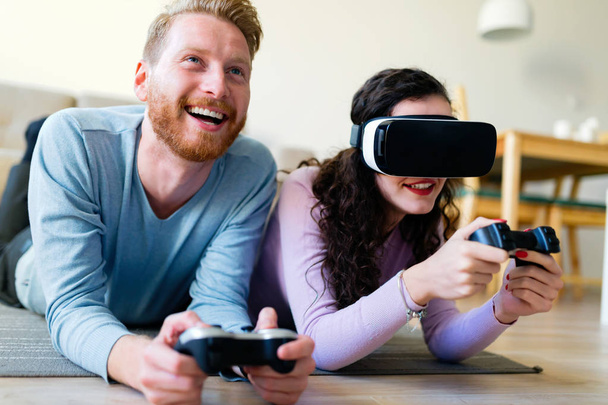 Happy young couple playing video games with virtual reality headsets at home - Valokuva, kuva