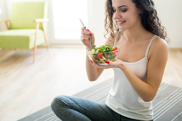 Νεαρή γυναίκα τρώει υγιεινά τρόφιμα μετά την προπόνηση σε γυμναστήριο - Φωτογραφία, εικόνα