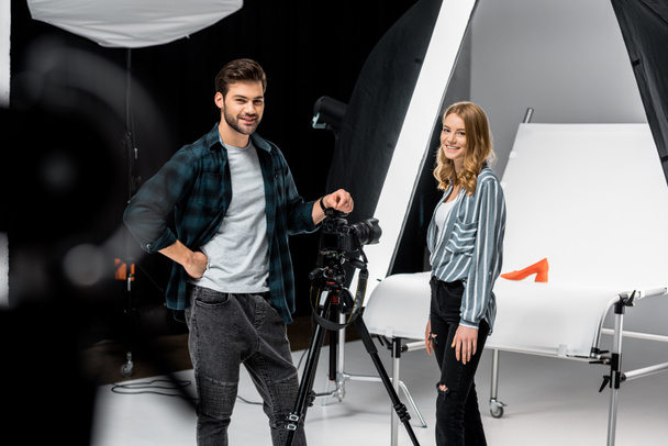 onnellisia nuoria valokuvaajia seisoo lähellä ammattimaisia valokuvauslaitteita ja hymyilee kameralle studiossa
  - Valokuva, kuva
