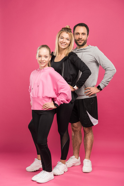 athletic parents and daughter posing in sportswear, isolated on pink - Fotoğraf, Görsel