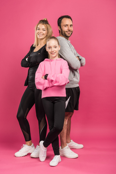 beautiful athletic family in sportswear posing with crossed arms, isolated on pink - Photo, Image