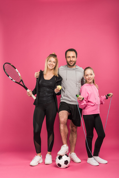 sporty family with sport equipment on pink - 写真・画像