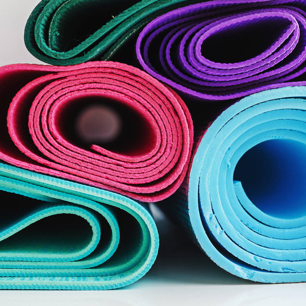 gestapelte Yogamatten in verschiedenen hellen Farben, Fitness-Hintergrund in einem quadratischen Rahmen - Foto, Bild