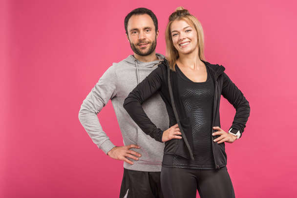 happy couple posing in sportswear isolated on pink - Fotó, kép