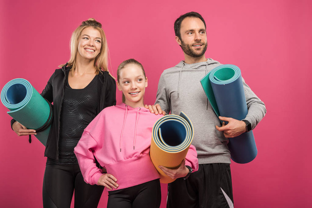 sporty family with daughter holding fitness mats, isolated on pink - Foto, Bild