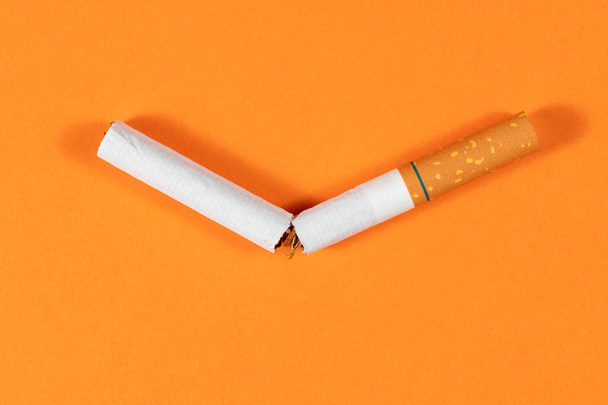 Tobacco Cigarette broken close up with orange background - Foto, Imagen