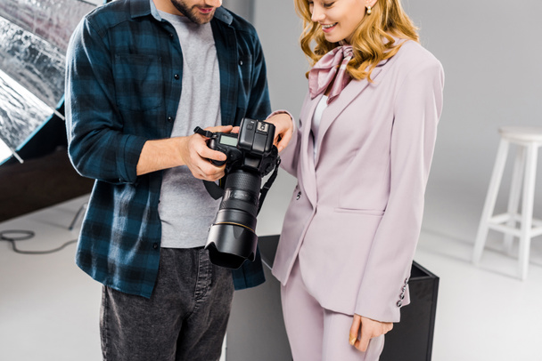 abgeschnittene Aufnahme lächelnder junger Fotograf und Model mit gemeinsamer Fotokamera - Foto, Bild