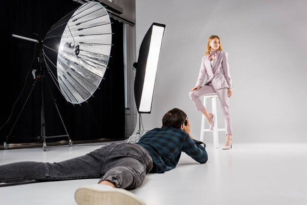 photographer lying and shooting beautiful female model in photo studio - Photo, image