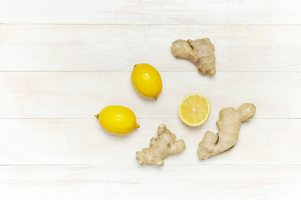 Fresh ginger root and lemon on white wooden background. Flat lay, top view, copy space. Minimalistic style, seasoning, spice, ingredient for tea. Concept healthy food, medicine improving immunity - Photo, image