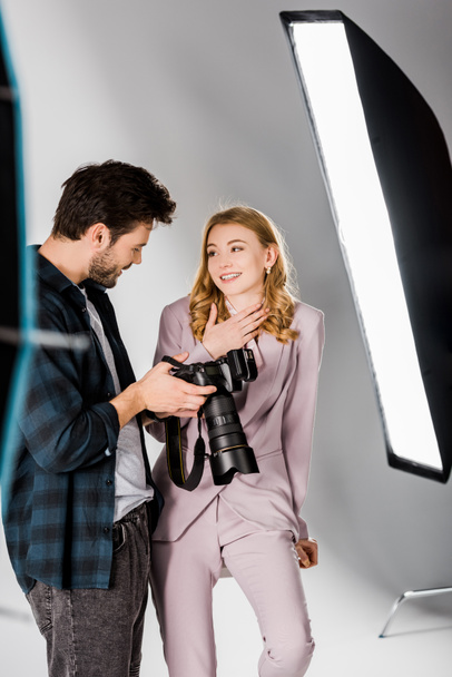 glimlachend jonge fotograaf en mooie model controle foto's op de camera in de studio  - Foto, afbeelding