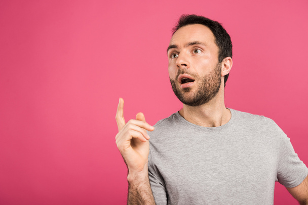 portrait of handsome man having idea and pointing up, isolated on pink  - 写真・画像