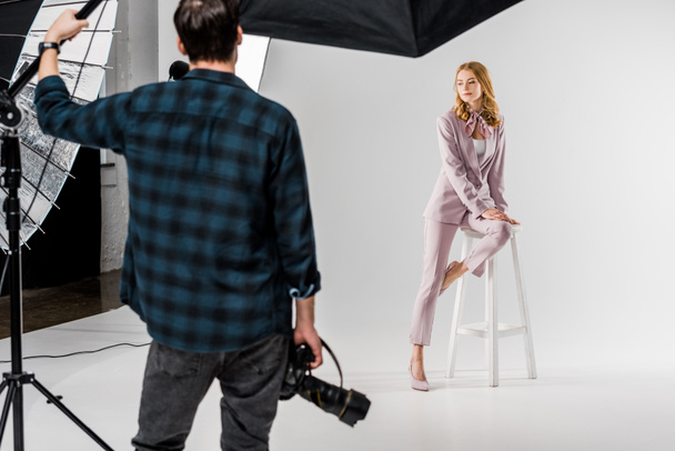 back view of photographer holding camera and model posing in studio - 写真・画像