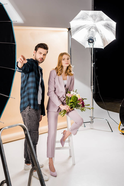 young photographer pointing with finger and showing something to beautiful female model in photo studio - Φωτογραφία, εικόνα