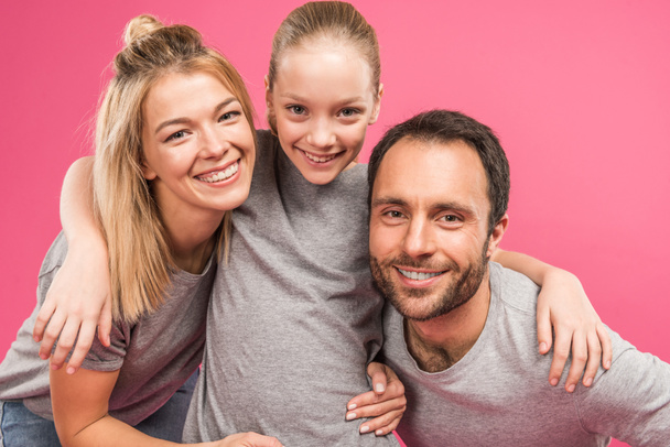 attractive happy daughter embracing her parents, isolated on pink - Photo, Image