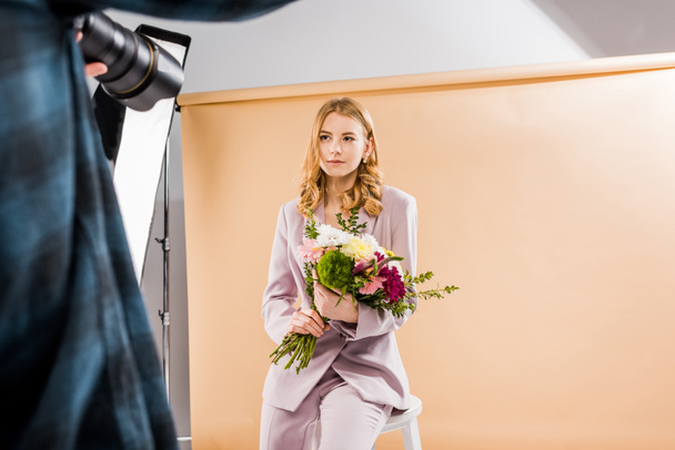 recortado disparo de fotógrafo disparo joven modelo femenino con flores en estudio de fotos
   - Foto, imagen