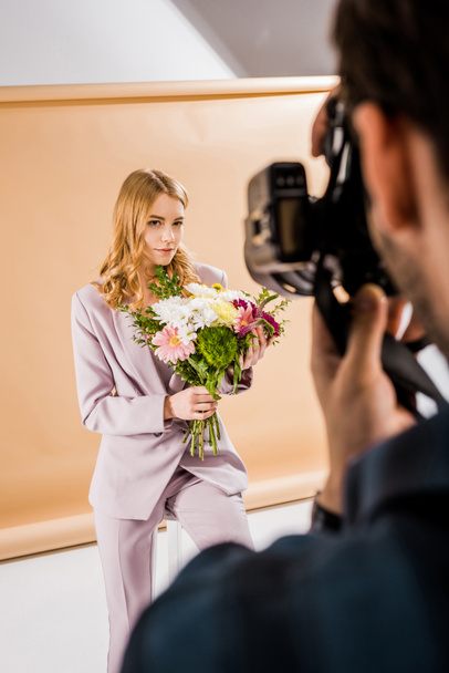花写真スタジオでポーズをとって若い女性モデルを撮影するカメラマンのショットをトリミング   - 写真・画像