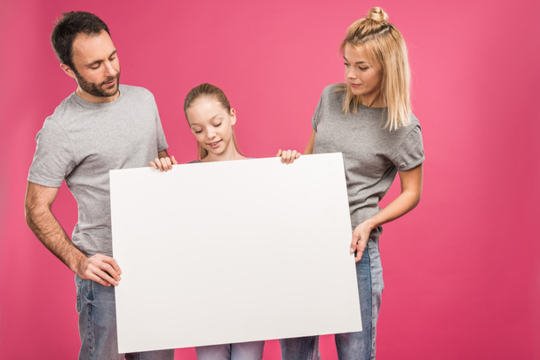 family posing with blank placard, isolated on pink - Фото, изображение