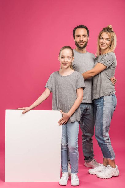 beautiful family posing with empty placard, isolated on pink - Foto, Imagem