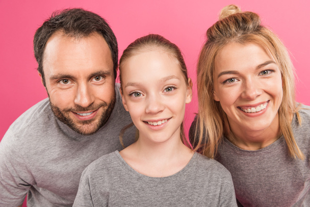 beautiful mother and father with happy daughter, isolated on pink - Foto, Bild