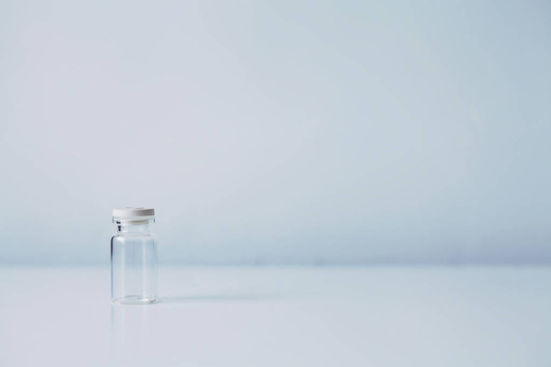 Old glass vial empty with a lot of copy space on blueish white blurred background - Foto, afbeelding