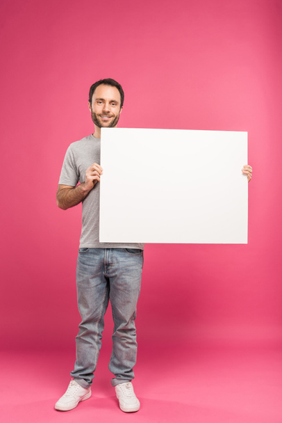 handsome smiling man posing with blank board, isolated on pink - Foto, Imagem