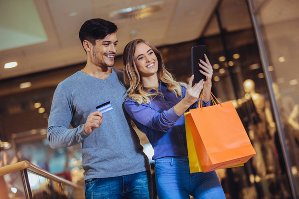 Portrait d'un couple heureux montrant leur nouvelle carte de crédit au centre commercial
 - Photo, image