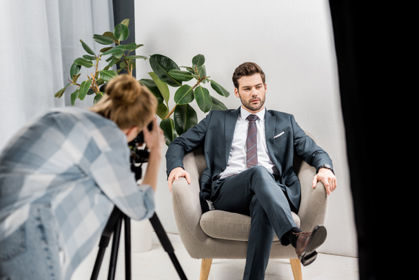 young female photographer shooting handsome businessman in studio  - Foto, Bild