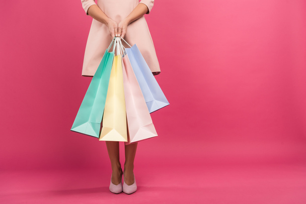 partial view of girl with shopping bags, isolated on pink - Photo, Image